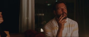 Movie still from “Everybody Loves Jeanne” (2022), directed by Céline Devaux – A man sitting in front of a window with his hand to his face; Close Up shot, Low angle