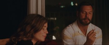 Movie still from “Everybody Loves Jeanne” (2022), directed by Céline Devaux – A woman sitting next to a man in front of a window at night; Close Up shot, Over the shoulder angle