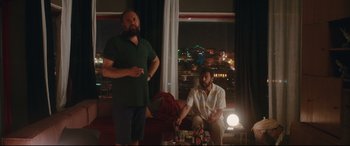 Movie still from “Everybody Loves Jeanne” (2022), directed by Céline Devaux – Two men sitting in front of a window at night; Wide shot, Over the shoulder angle
