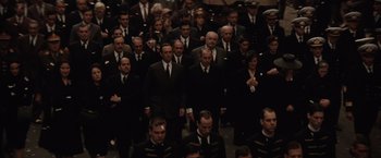 Movie still from “Evita” (1996), directed by Alan Parker – A group of men in suits and ties standing in a crowd; Wide shot, High angle