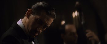 Movie still from “Evita” (1996), directed by Alan Parker – A person wearing a suit and tie; Close Up shot, Low angle