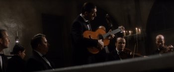 Movie still from “Evita” (1996), directed by Alan Parker – A man in a tuxedo playing an instrument; Medium shot, Low angle