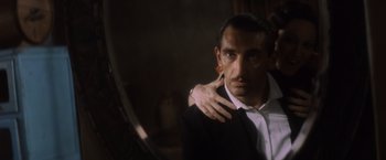 Movie still from “Evita” (1996), directed by Alan Parker – A person wearing a suit and tie; Close Up shot, Over the shoulder angle