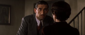 Movie still from “Evita” (1996), directed by Alan Parker – A man in a suit and tie looking in the mirror; Close Up shot, Over the shoulder angle