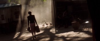 Movie still from “Evita” (1996), directed by Alan Parker – A woman walking down the street with a bag of luggage; Wide shot, High angle