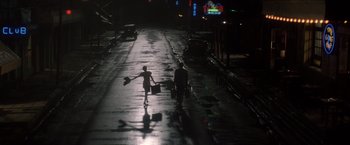 Movie still from “Evita” (1996), directed by Alan Parker – A man and a woman walking down a street at night with suitcases; Wide shot, High angle