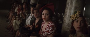 Movie still from “Evita” (1996), directed by Alan Parker – A group of women sitting next to each other in a room; Medium shot, Over the shoulder angle