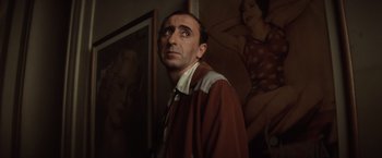 Movie still from “Evita” (1996), directed by Alan Parker – A man standing in front of a wall with pictures on the wall; Close Up shot, Low angle