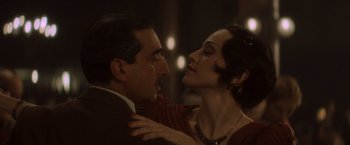 Movie still from “Evita” (1996), directed by Alan Parker – A man and a woman embracing each other in front of lights; Close Up shot, Low angle