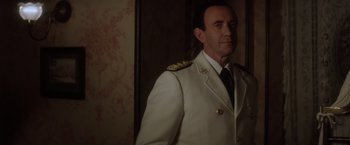 Movie still from “Evita” (1996), directed by Alan Parker – A man in a military uniform standing in front of a wall; Close Up shot, Over the shoulder angle