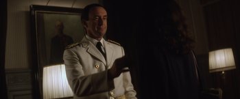 Movie still from “Evita” (1996), directed by Alan Parker – A man in a white suit is holding a cell phone; Medium shot, Over the shoulder angle