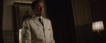 Movie still from “Evita” (1996), directed by Alan Parker – A man in a white suit standing in a dark room; Close Up shot, Low angle