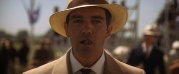 Movie still from “Evita” (1996), directed by Alan Parker – A person wearing a suit and a hat; Close Up shot, Low angle