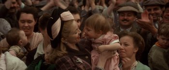 Movie still from “Evita” (1996), directed by Alan Parker – A woman holding a baby in a crowd of onlookers; Close Up shot, Over the shoulder angle