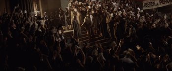 Movie still from “Evita” (1996), directed by Alan Parker – A group of people standing in front of a crowd of people; Wide shot, High angle