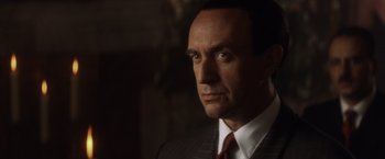 Movie still from “Evita” (1996), directed by Alan Parker – A man in a suit and tie; Close Up shot, Low angle