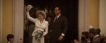 Movie still from “Evita” (1996), directed by Alan Parker – A man and a woman are waving at the camera; Medium shot, Low angle