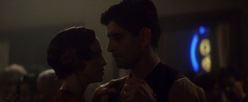 Movie still from “Evita” (1996), directed by Alan Parker – A man and a woman face to face in a dark room; Close Up shot, Low angle