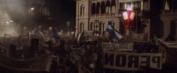 Movie still from “Evita” (1996), directed by Alan Parker – A large group of people protesting in front of a large building; Extreme Wide shot, High angle