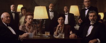 Movie still from “Evita” (1996), directed by Alan Parker – A group of people sitting at a table with lamps; Medium shot, Low angle