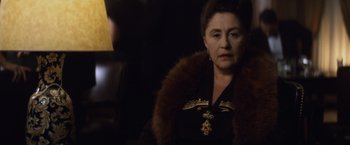Movie still from “Evita” (1996), directed by Alan Parker – An older woman wearing a black dress and a fur coat; Close Up shot, Over the shoulder angle