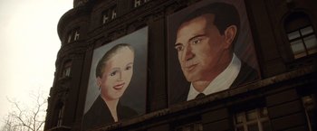 Movie still from “Evita” (1996), directed by Alan Parker – A painting of a man and a woman on the side of a building; Extreme Close Up shot, Low angle