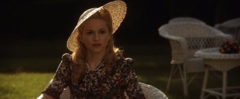 Movie still from “Evita” (1996), directed by Alan Parker – A woman in a straw hat is sitting in the sunlight; Close Up shot, Over the shoulder angle