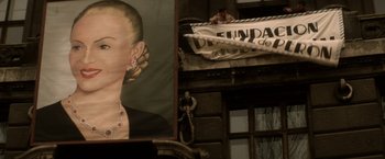 Movie still from “Evita” (1996), directed by Alan Parker – A woman's face in front of a building with an advertisement; Close Up shot, Low angle