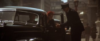 Movie still from “Evita” (1996), directed by Alan Parker – A woman in a black dress getting out of a car; Wide shot, Low angle