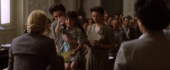 Movie still from “Evita” (1996), directed by Alan Parker – A group of people standing in front of a crowd of people; Medium shot, Over the shoulder angle