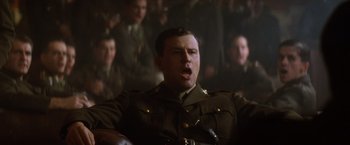 Movie still from “Evita” (1996), directed by Alan Parker – A man in a military uniform with his mouth wide open; Close Up shot, Low angle