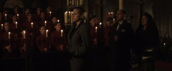 Movie still from “Evita” (1996), directed by Alan Parker – A group of people standing in front of candles in a church; Medium shot, Low angle