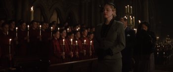 Movie still from “Evita” (1996), directed by Alan Parker – A woman standing in front of a group of people holding lit candles; Medium shot, Low angle