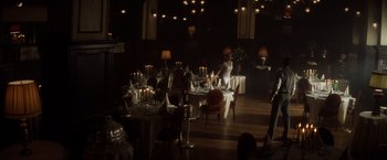 Movie still from “Evita” (1996), directed by Alan Parker – A group of people sitting at a table in a room; Wide shot, Low angle