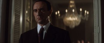 Movie still from “Evita” (1996), directed by Alan Parker – A person wearing a suit and tie; Close Up shot, Low angle