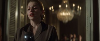 Movie still from “Evita” (1996), directed by Alan Parker – A woman in a brown jacket is holding a microphone; Close Up shot, Low angle