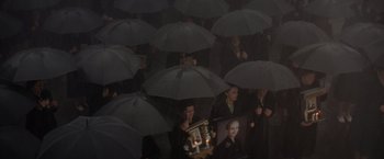 Movie still from “Evita” (1996), directed by Alan Parker – A group of people standing under black umbrellas; Wide shot, High angle