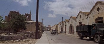 Movie still from “Exodus” (1960), directed by Otto Preminger – An old car drives down the street in an urban setting; Extreme Wide shot, High angle