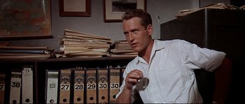 Movie still from “Exodus” (1960), directed by Otto Preminger – A man in a white dress shirt is holding a cigarette; Medium shot, Low angle