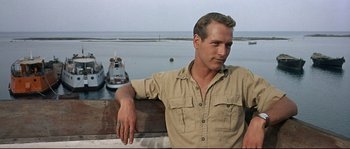 Movie still from “Exodus” (1960), directed by Otto Preminger – A man sitting on a ledge next to a body of water; Medium shot, Low angle