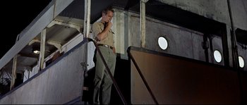 Movie still from “Exodus” (1960), directed by Otto Preminger – A man standing on a set of stairs in the dark; Medium shot, Low angle