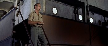 Movie still from “Exodus” (1960), directed by Otto Preminger – A man smoking a cigarette while standing on a set of stairs; Medium shot, Low angle