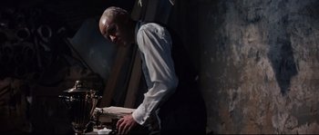 Movie still from “Exodus” (1960), directed by Otto Preminger – An older man standing in front of a table; Medium shot, Low angle