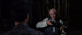 Movie still from “Exodus” (1960), directed by Otto Preminger – An older man holding a glass of beer in front of a younger man; Medium shot, Over the shoulder angle