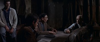 Movie still from “Exodus” (1960), directed by Otto Preminger – A group of men sitting around a table; Medium shot, Over the shoulder angle