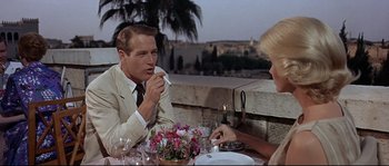 Movie still from “Exodus” (1960), directed by Otto Preminger – A man and a woman sitting at a dinner table; Medium shot, Over the shoulder angle