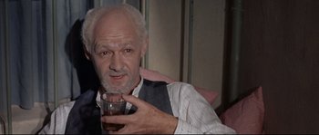 Movie still from “Exodus” (1960), directed by Otto Preminger – An older man holding a glass of beer; Close Up shot, High angle