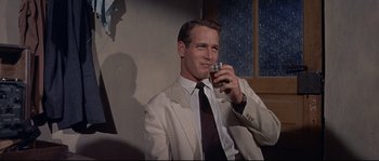 Movie still from “Exodus” (1960), directed by Otto Preminger – A man in a suit and tie holding a glass of wine; Medium shot, Low angle