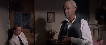 Movie still from “Exodus” (1960), directed by Otto Preminger – An older man standing in a room holding a glass; Medium shot, Over the shoulder angle