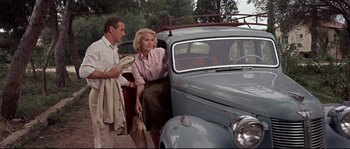 Movie still from “Exodus” (1960), directed by Otto Preminger – A man and a woman standing next to a car; Medium shot, Low angle